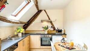 A kitchen with a herringbone floor, wooden cabinets, a built-in oven, a microwave, and a dining table with chairs. - 1 bedroom accommodation in Newbridge-on-Wye, near Builth Wells (Newbridge-on-Wye, near Builth Wells)