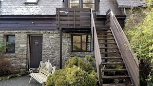A stone building with a wooden staircase leading to a balcony. - 1 bedroom accommodation in Newbridge-on-Wye, near Builth Wells (Newbridge-on-Wye, near Builth Wells)