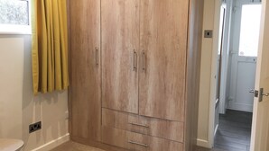 Ein Zimmer mit einem Holzschrank, einem kleinen Tisch und einer Tür zu einem anderen Raum.