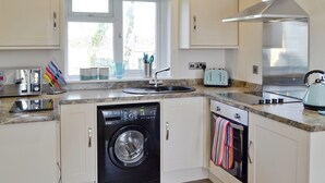 Eine kompakte Küche mit Waschmaschine, Backofen und Toaster.