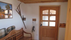 A wooden bench with a plaid cushion, a wooden door with glass panels, and a wall-mounted coat rack. - Familiy friendly holiday apartement in a ski area (Sirnitz)