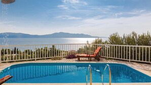Une piscine avec vue sur un plan d’eau et des montagnes en arrière-plan.