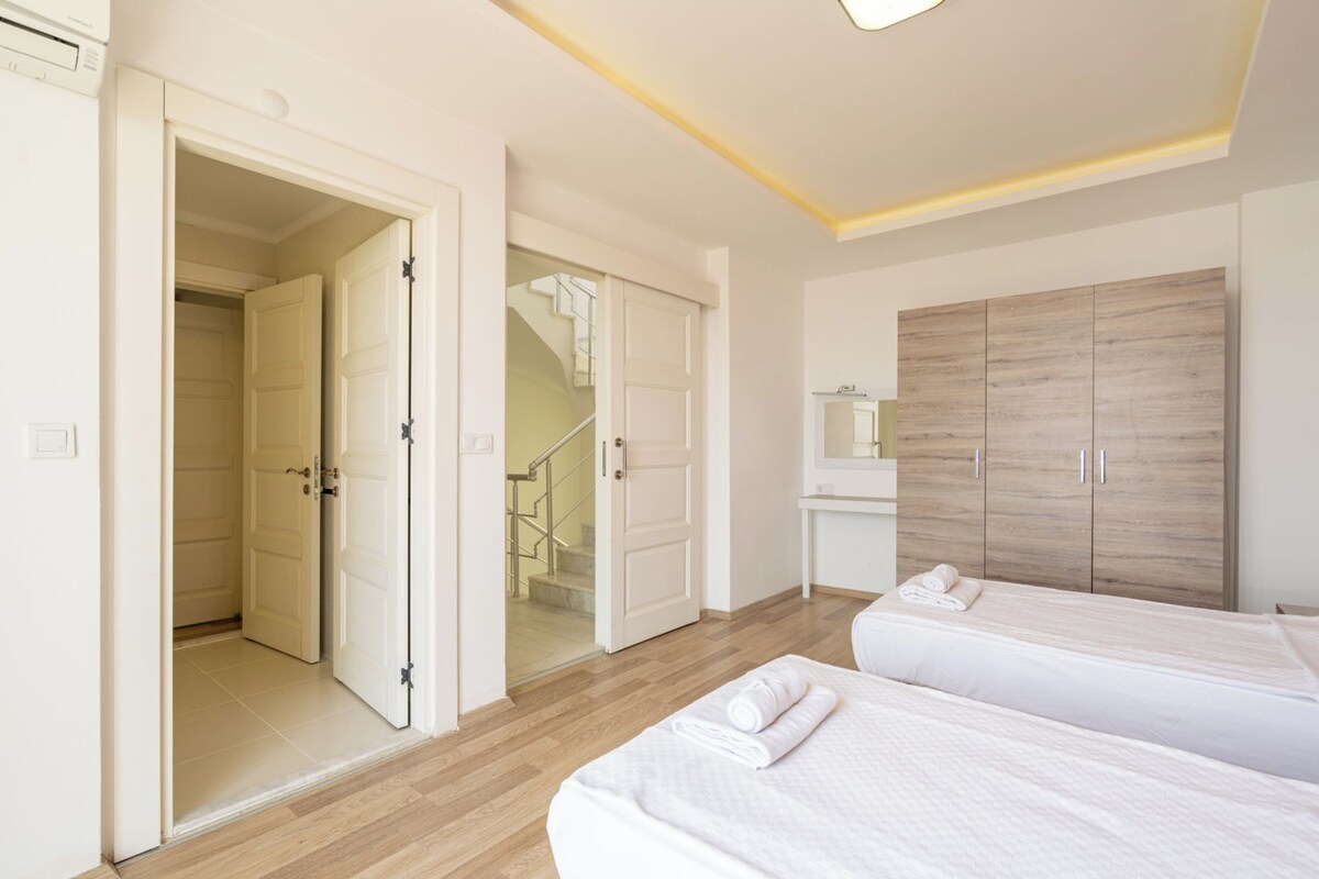 A bedroom with two beds, a wardrobe, and a bathroom.