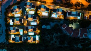 Vista aérea de una zona residencial con varias casas, cada una con piscina e iluminación exterior.