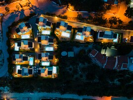 Vista aérea de una zona residencial con varias casas, cada una con piscina e iluminación exterior.