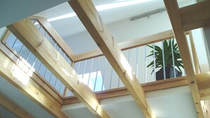 Ein Zimmer mit geneigter Decke, Holzbalken und einem Oberlicht.