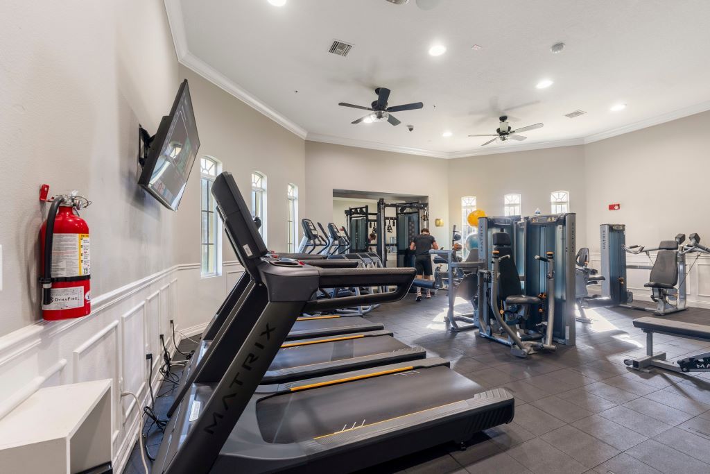 A gym with treadmills, weight machines, and a fire extinguisher on the wall.
