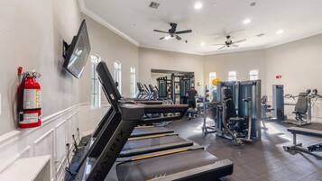 A gym with treadmills, weight machines, and a fire extinguisher on the wall.