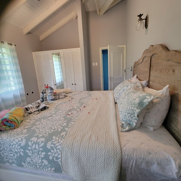 A bedroom with a large bed, a wooden headboard, and a blue door.