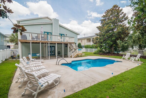 A residential property with a swimming pool, a covered patio, and a fenced yard.