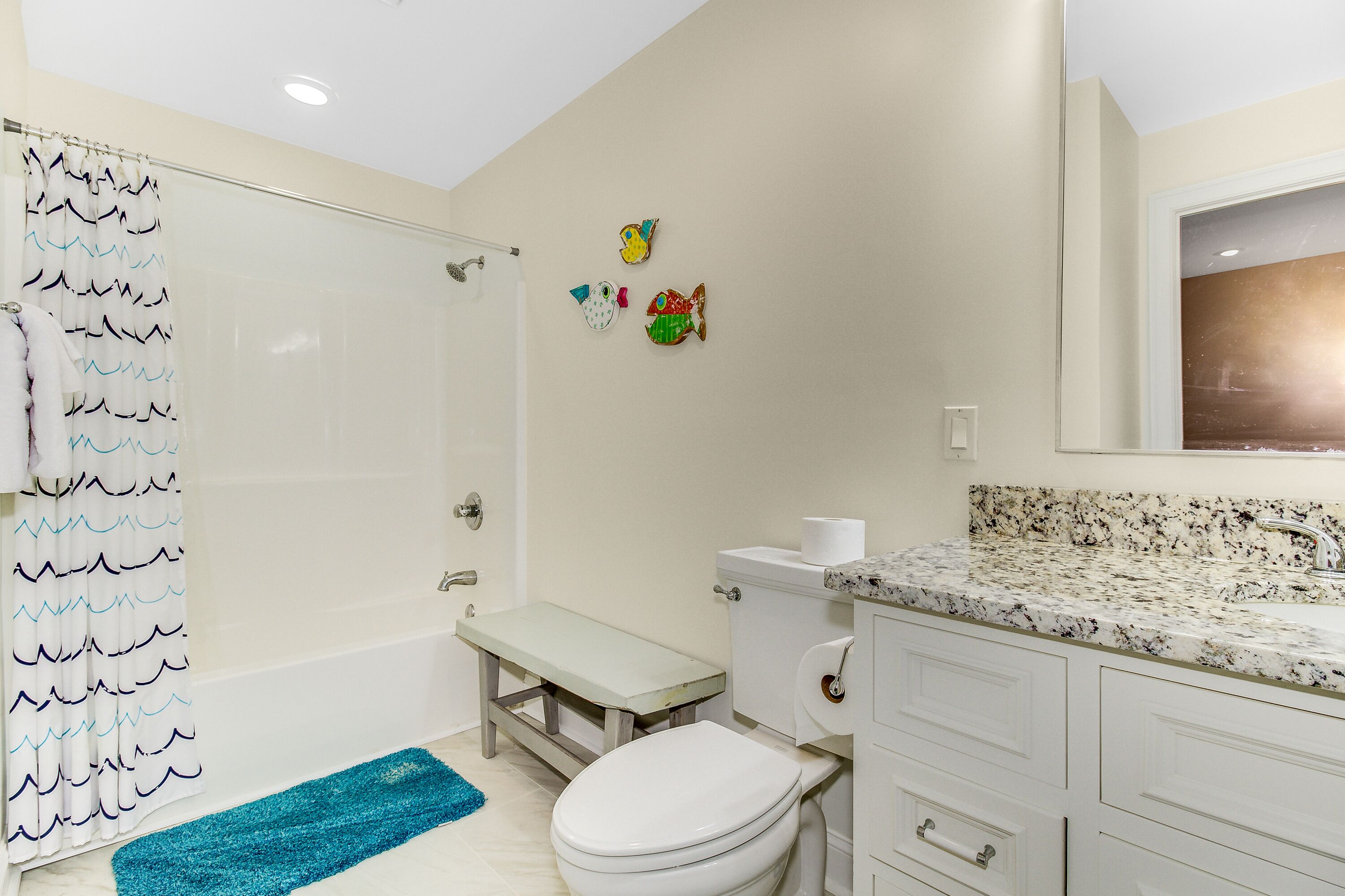 Une salle de bain équipée d’une douche, de toilettes, d’un lavabo et d’un banc.