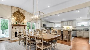 Una cocina amplia con una isla grande, muebles blancos y una pared decorativa de piedra.