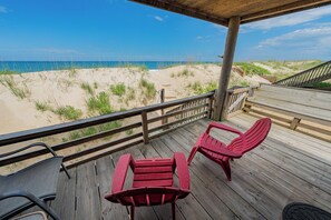 A wooden deck with two red chairs and a bench overlooking a beach with sand dunes and the ocean. - Oceanfront Cottage - 3 bedroom & 2 bathrooms - Great Ocean Views - Pet Friendly (Kill Devil Hills)