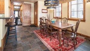 A dining area with a wooden table and chairs, a red patterned rug, and a chandelier. - Outpost: Grand View 491 - Air Conditioning (Jackson)