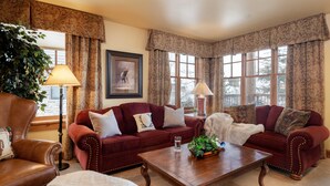 A cozy living room with a red sofa set, a wooden coffee table, and a large window with curtains. - Outpost: Grand View 491 - Air Conditioning (Jackson)