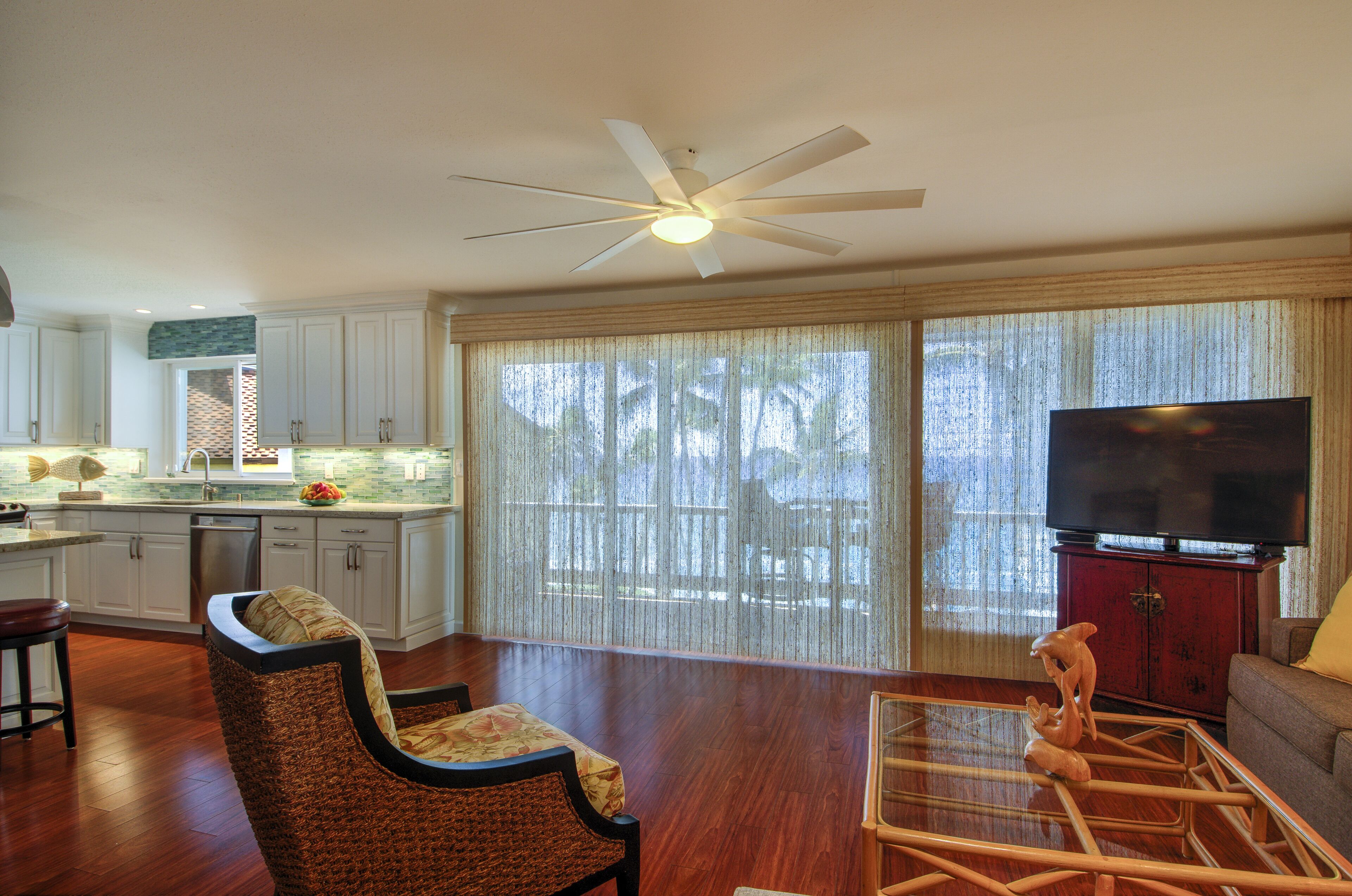 A spacious living area with a ceiling fan, a television, and a dining table.