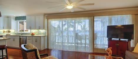 A spacious living area with a ceiling fan, a television, and a dining table.