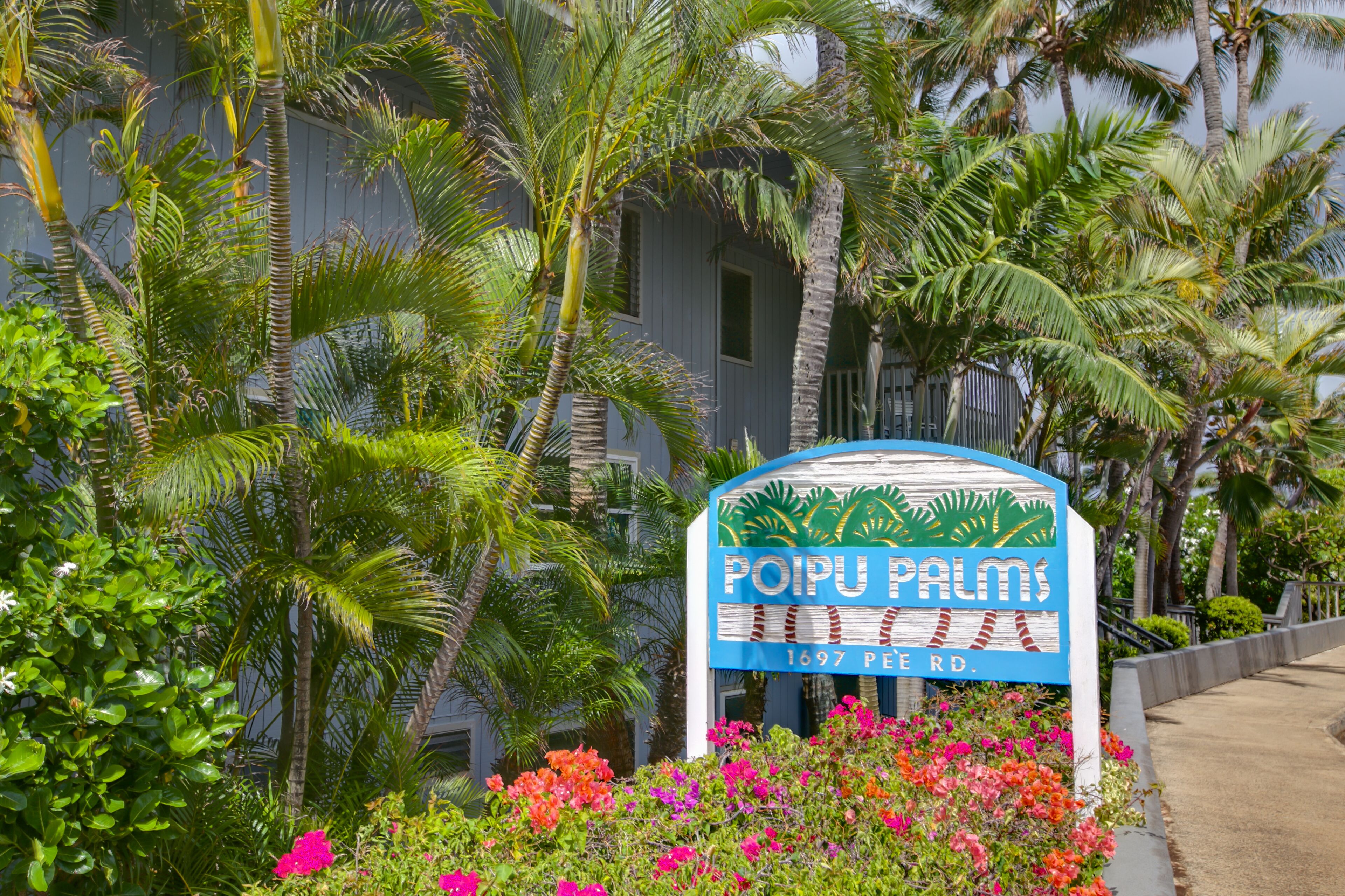 Señal de Poipu Palms, con un jardín tropical y palmeras.