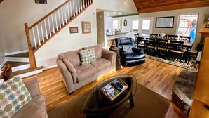 A spacious living room with a wooden staircase, a dining area, and a kitchen visible through an open door. - Relax & Unwind at the Chestatee River Retreat! Pet Friendly & Near Wineries (Dahlonega)