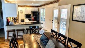 A modern kitchen with white cabinets, a black refrigerator, and a dining area with a wooden table and chairs. - Relax & Unwind at the Chestatee River Retreat! Pet Friendly & Near Wineries (Dahlonega)