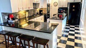 A kitchen with white cabinets, a black and white checkered floor, and a large island with stools. - Relax & Unwind at the Chestatee River Retreat! Pet Friendly & Near Wineries (Dahlonega)