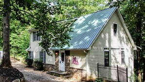 A two-story house with a metal roof, a front porch, and a black metal fence. - Relax & Unwind at the Chestatee River Retreat! Pet Friendly & Near Wineries (Dahlonega)
