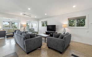 A modern living room with grey sofas, a flat-screen TV, and a ceiling fan. - Lakefront Beach Home + Pet Friendly, Grill & Bikes (Santa Rosa Beach)