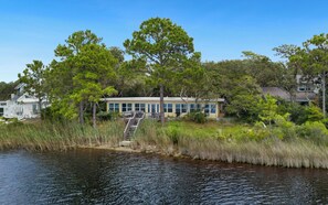 A lakeside property with a dock, a small building with large windows, and surrounding greenery.