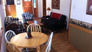 Un coin repas comprenant une table ronde en bois, quatre chaises et une sculpture décorative en bois.