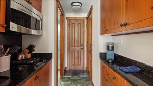 Una cocina con gabinetes de madera, microondas de acero inoxidable, cafetera Keurig y estufa a gas.