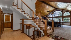 A multi-level wooden staircase with a view of the outdoors through large windows.