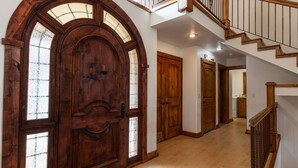 A wooden front door with glass panels, a staircase with wooden railings, and a hallway leading to a laundry area.