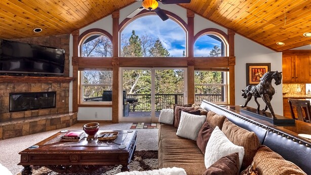 A spacious living room with a fireplace, large windows, and a cozy seating area.