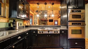 Una cocina moderna con armarios oscuros, una estufa central y hornos integrados.