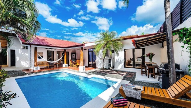 A poolside area with a rectangular pool, wooden lounge chairs, a hammock, and a barbecue grill. - Casa Tropical☙Remodeled Beach Oasis Perfect for resting and relaxing ❧ (Tamarindo)