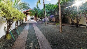 A pathway leading to a building with a red roof, surrounded by palm trees and tropical plants. - Casa Tropical☙Remodeled Beach Oasis Perfect for resting and relaxing ❧ (Tamarindo)