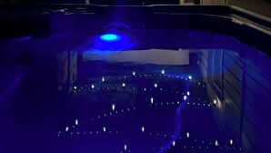 Piscina com luzes de corda sobre a cabeça e um mural na parede.