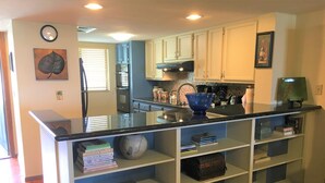 Una cocina con una isla central, estantes empotrados y un reloj en la pared.
