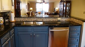 Una cocina con armarios azul oscuro, un refrigerador de acero inoxidable y un salpicadero de azulejos.