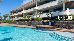 Un hotel con piscina, varios balcones y una pared de piedra.