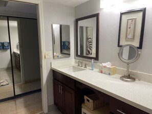 A bathroom with a white sink, two mirrors, a towel rack, and a basket under the counter. - Fabulous Ocean Views : Whales : Dolphins : Big Island Fun! (Kailua-Kona)