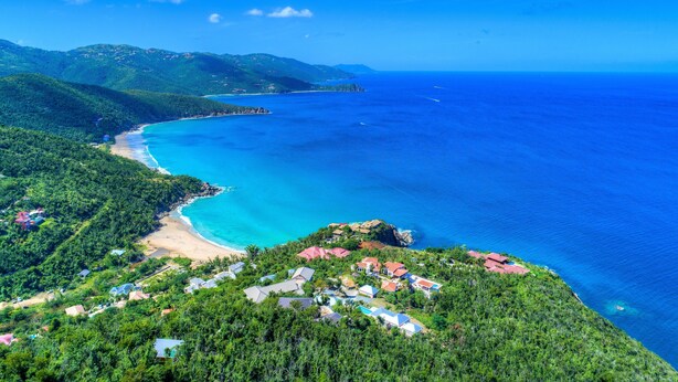 A coastal area with a beach, houses, and a clear view of the ocean.