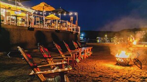 A beachside seating area with lounge chairs and a fire pit.