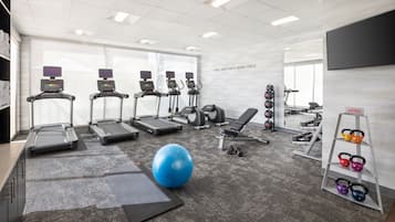 Et fitnessrum med løbebånd, en motionscykel, en romaskine, håndvægte og en blå træningsbold.