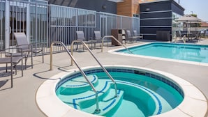 Un área de piscina con jacuzzi, sillas de descanso y una zona de estar cubierta.