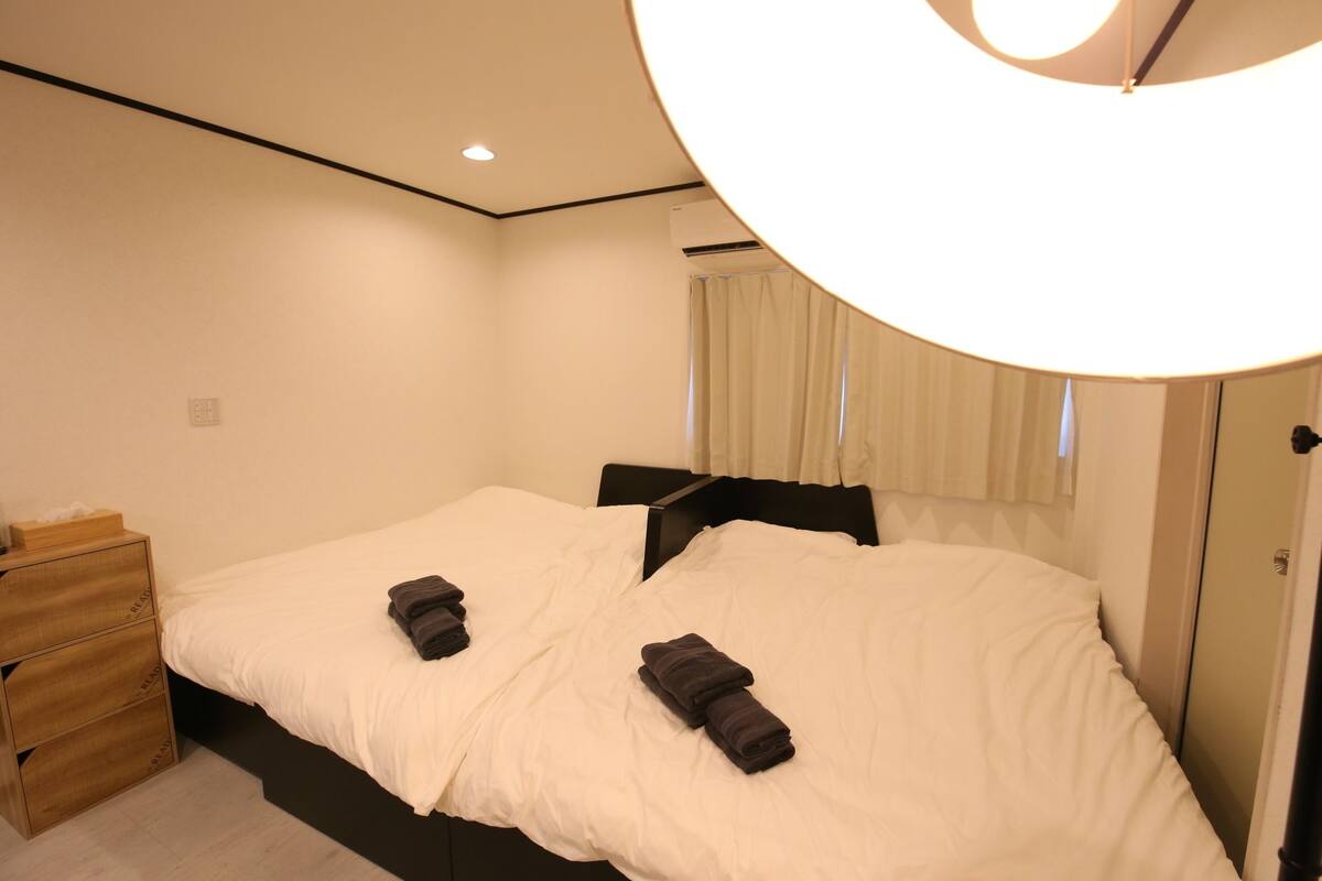 Een slaapkamer met een bed, een houten nachtkastje en een wandairconditioner.