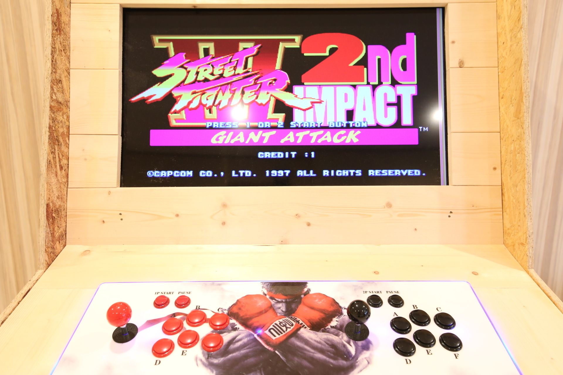 A vintage arcade cabinet for Street Fighter 2nd Impact with a joystick and buttons labeled A-F.