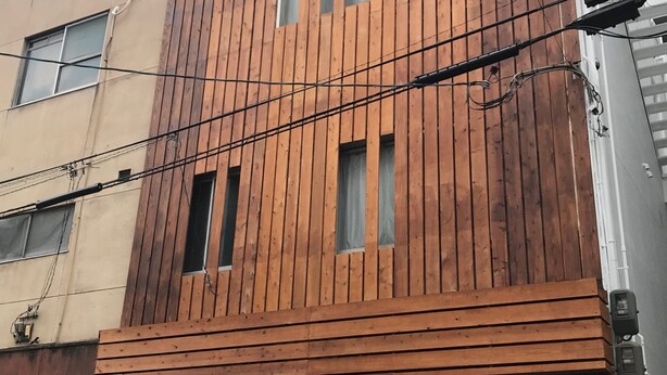 A building with a wooden facade, multiple windows, and visible electrical wires. - Shizuka - Kozu (Osaka)