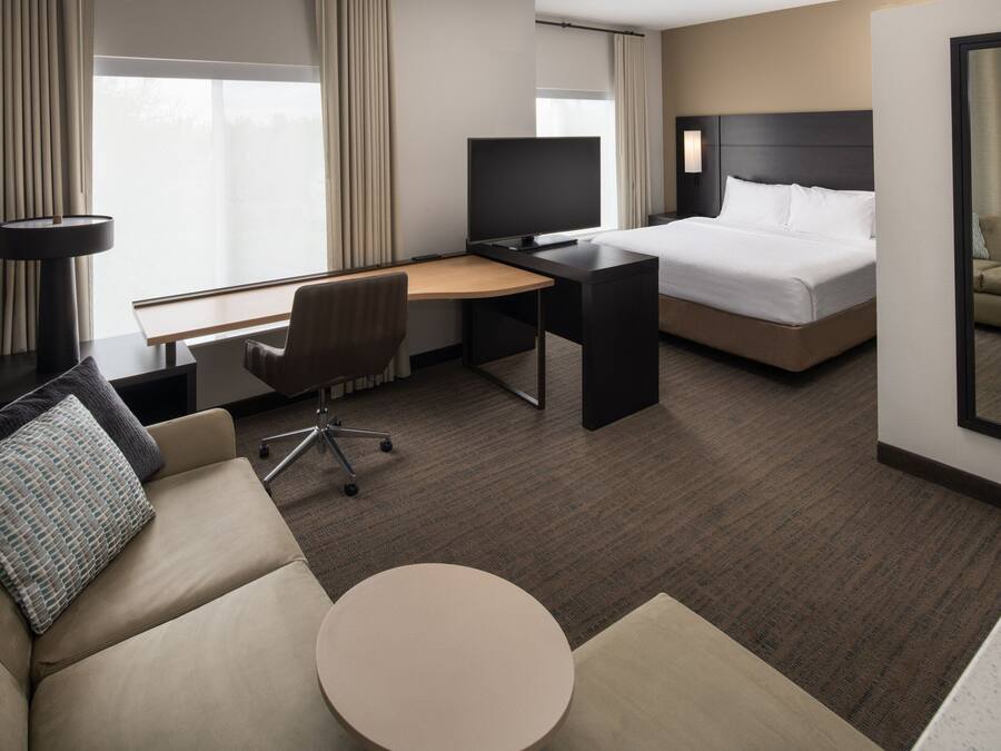 A hotel room with a bed, a desk with a chair, a round table, and a sofa.
