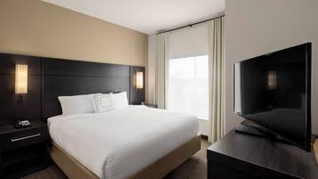 A hotel room with a large bed, a flat-screen TV, a nightstand, and a window with curtains.